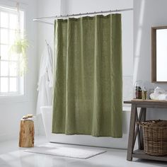 a bathroom with a green shower curtain next to a white bath tub and wooden stool