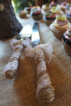 a table topped with lots of cupcakes covered in burlocks and ribbons