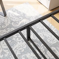 a metal bed frame sitting on top of a carpeted floor next to a laptop computer