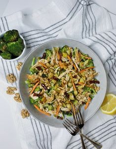 a white plate topped with salad next to a bowl of broccoli