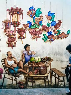 two people sitting at a table in front of a mural