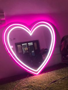 a heart shaped neon sign in the corner of a room with a mirror on it