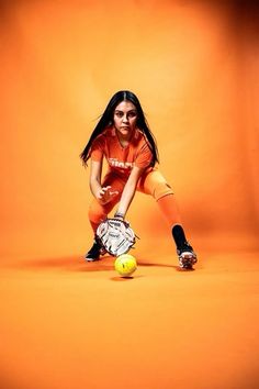 a woman in an orange shirt is playing with a tennis racket and ball on an orange background