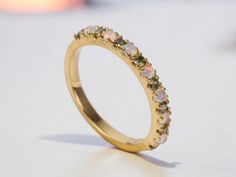 a yellow gold ring with white and green stones on the inside, sitting on a table