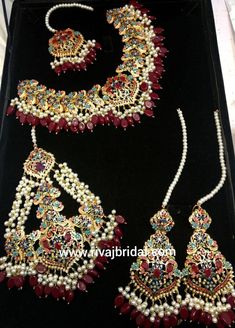 an elaborate necklace and earring set with red, white and gold beads on display