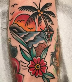 a colorful tattoo on the leg of a person with flowers and palm trees in the background