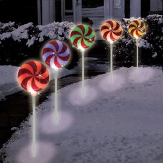 four lighted lollipops in the snow at night