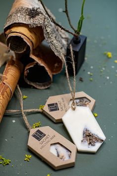 three tags are hanging on a piece of wood next to a pipe and some flowers