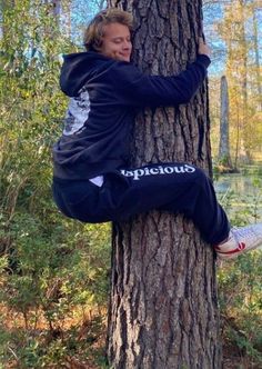 a man sitting on top of a tree in the woods