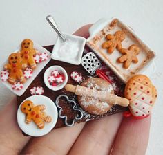 a hand holding a miniature tray with cookies and pretzels on it, along with other decorations