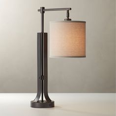 a table lamp with a white shade on it and a black metal frame around the base