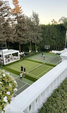 an aerial view of a tennis court with people playing on the grass and trees in the background