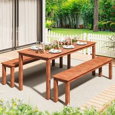 a wooden table with two benches in front of it and a white fence behind it