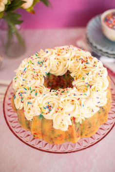 a cake with white frosting and sprinkles sitting on a glass plate