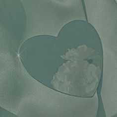 a heart - shaped piece of glass with flowers in it is reflected on the fabric