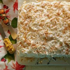 there is a large cake with white frosting on the table next to a knife