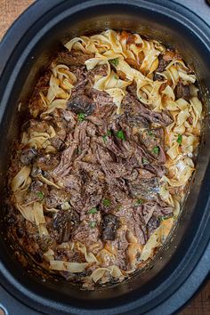 a crock pot filled with beef and noodles