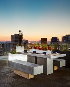 an outdoor dining table with benches and potted plants on the top of a roof