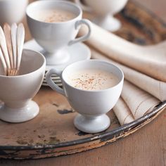 white cups and spoons are sitting on a tray