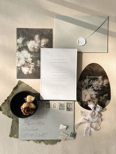 wedding stationery and envelopes laid out on top of each other with flowers in them