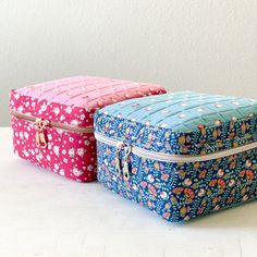 two colorful bags sitting next to each other on top of a white table with a wall in the background