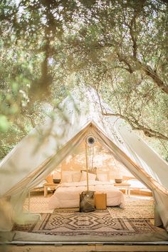 a tent is set up in the middle of a field with trees and benches around it