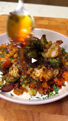 a white plate topped with broccoli and cauliflower on top of a wooden table