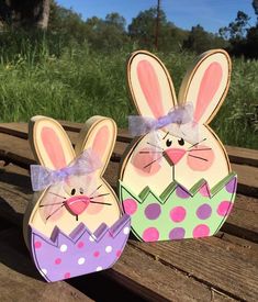 two paper rabbits sitting on top of a wooden bench