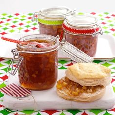 two jars of jam and a sandwich on a plate with a red striped tablecloth