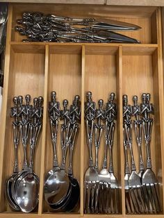 spoons and forks are arranged in an open drawer