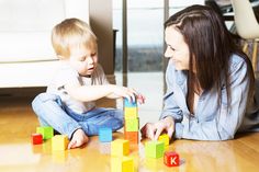 a woman and child playing with blocks on the floor