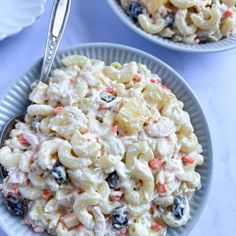 two bowls filled with pasta salad on top of a blue table cloth next to silverware