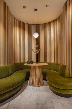 a green couch sitting next to a wooden table in a room with wood slats on the walls