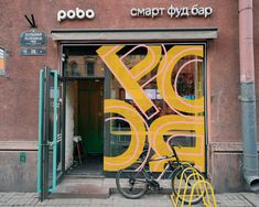 a bicycle parked in front of a building with large letters on the door and windows