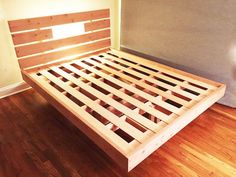 a wooden bed frame sitting on top of a hard wood floor next to a wall