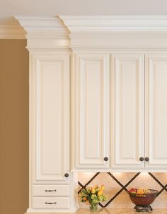 a bowl of fruit is sitting on the counter in this white kitchen with cabinets and drawers