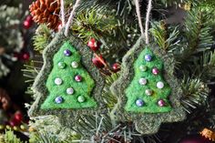 two ornaments are hanging from a christmas tree ornament in the shape of trees