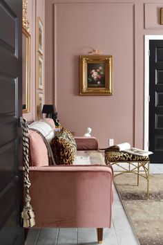 a living room with pink walls and leopard print pillows on the couch, gold framed art