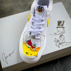 These customs are my original take on "Scrooge McDuck Money Bin"! Perfect lifestyle statement with your favorite Duckburg billionaire.  All of my customs are thoroughly prepped, spending several hours getting them ready for painting. Once ready, I use the top level industry standard Angelus Direct products. These paints allow your customs to hold up on a daily basis.  And I finally apply several sealing coats from LK Topcoat finishers. This insures the shoes are scratch and UV resistant. As well as waterproof and chemical resistant. Each custom painted takes on average 8-10 hours from start to completion. With these themed customs, you my change the base color or add / subtract elements around the shoe. While waiting for the shoes to come into the studio. I will briefly work with you to go Custom Sneakers With Round Toe For Skateboarding, Customized Sneakers For Streetwear With Round Toe, Customized Sneakers With Round Toe For Streetwear, Custom Sneakers For Streetwear, Custom White Skateboarding Sneakers, Custom Lace-up Sneakers, Customized Round Toe Sneakers For Streetwear, Yellow Low-top Sneakers With Custom Artwork, Custom Yellow Sneakers For Streetwear