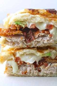 two sandwiches stacked on top of each other with meat, cheese and vegetables in them