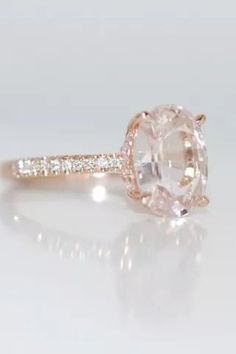 an oval cut diamond ring with pave diamonds on the band and side stones set in 18k rose gold