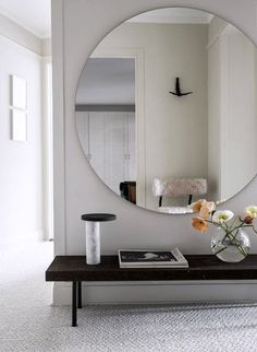 a vase with flowers on a table in front of a mirror