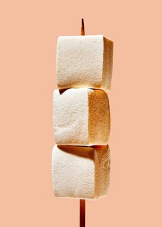 three marshmallows stacked on top of each other in front of a pink background