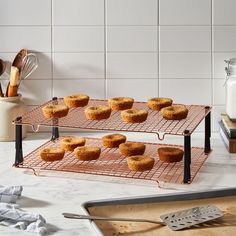 several trays of muffins on a wire rack with utensils next to them