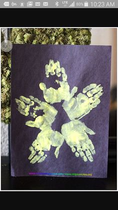 an image of a hand print on a piece of purple paper with yellow paint and green ink