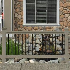 a cat sitting on top of a wooden bench next to a stone wall and window