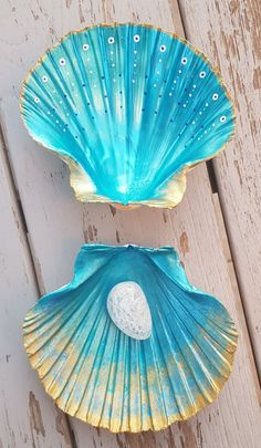 two blue seashells sitting on top of a white wooden table next to each other