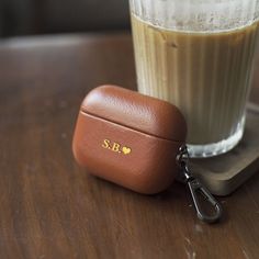 a brown case sitting on top of a wooden table next to a glass filled with liquid