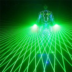 a man is standing in the dark with green laser lights on his face and head