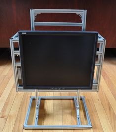 a flat screen tv sitting on top of a metal stand in front of a wooden floor